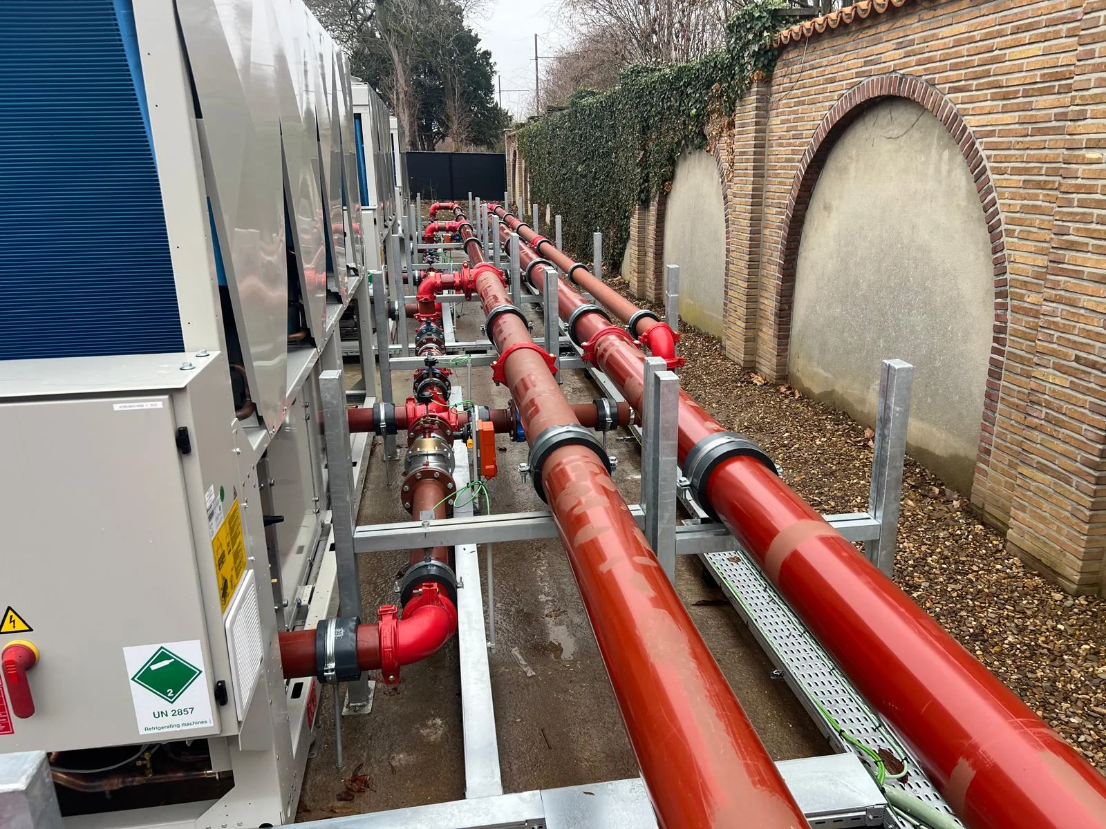 Industrial facility with large-diameter steel pipework and installation crew at work